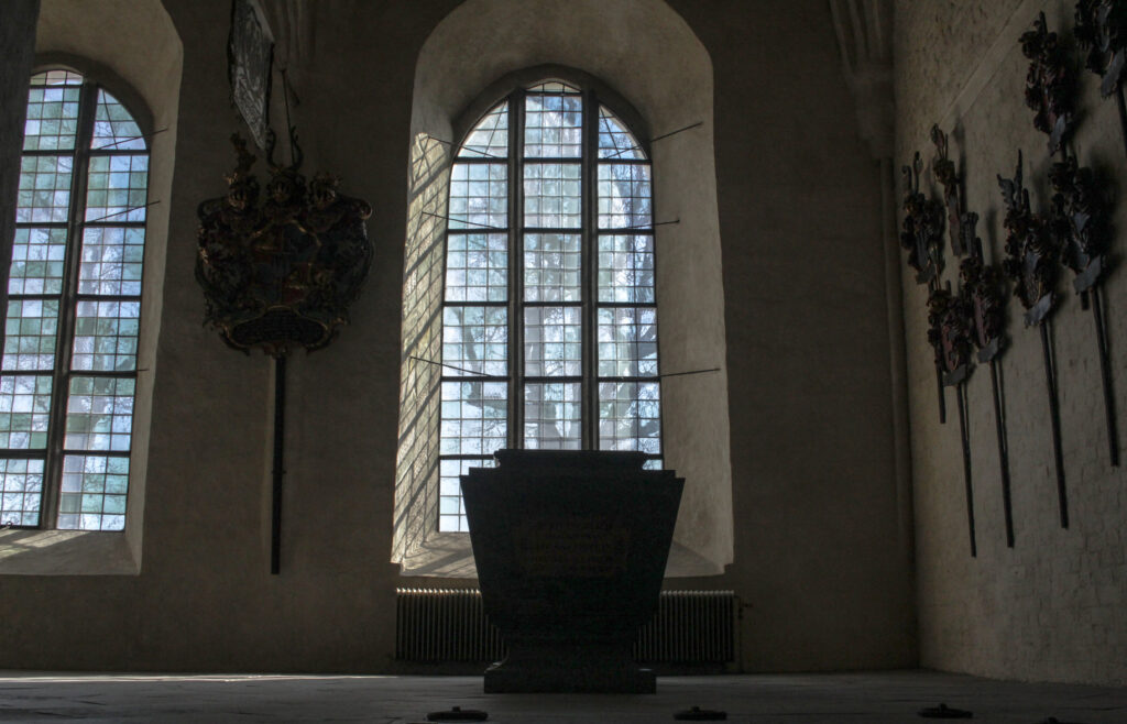 en kista i strängnäskyrka i bakgrunden är två stora kyrkofönster man tydligt ser ut ur