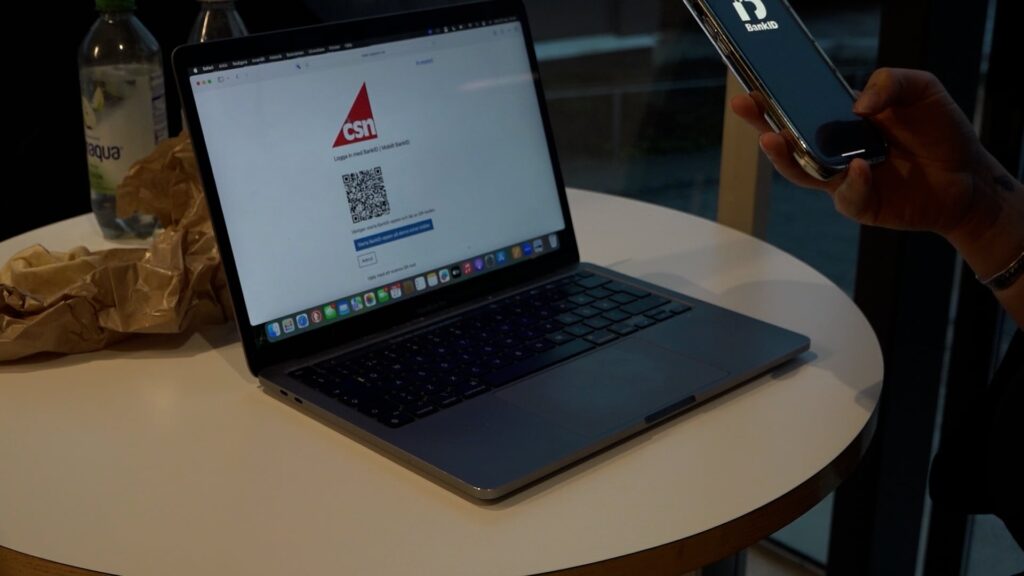 Dator med sidan CSN uppe och en person med Bank-ID framme